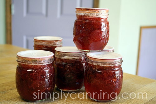 Decorative jars of strawberry jam sitting on the countertop.