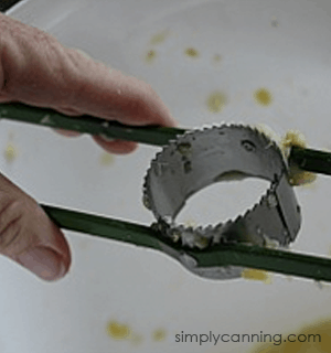 The round corn stripping blade mounted between two metal bars to hold it in place.