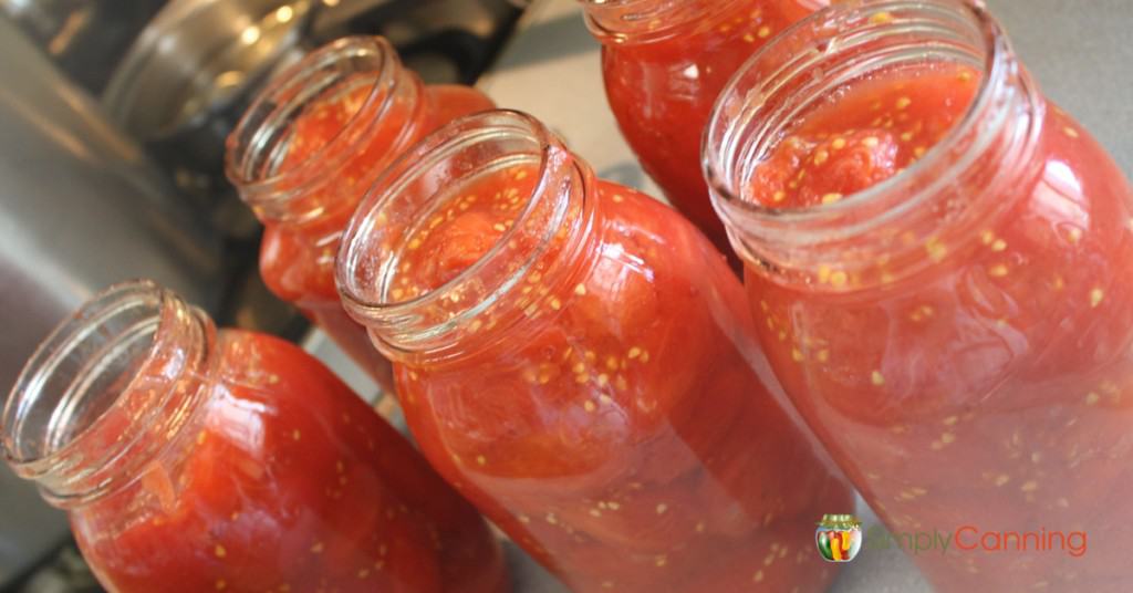 Open quart canning jars filled with tomatoes.