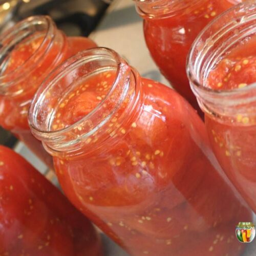 Open quart canning jars filled with tomatoes.