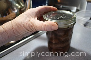 Screwing a ring on a jar packed with venison cubes.