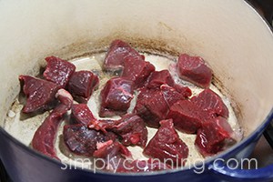 Browning pieces of venison in a Dutch oven.
