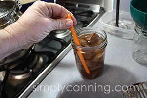 Removing bubbles from a jar hot packed with venison cubes.