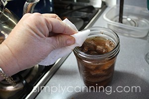 Wiping the rim of a jar with a wet paper towel.