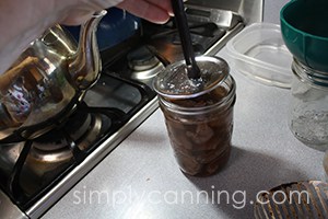 Placing a flat lid on a jar of canned venison.