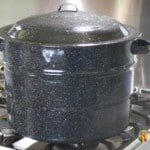 Black graniteware water bath canner sitting on the stove.