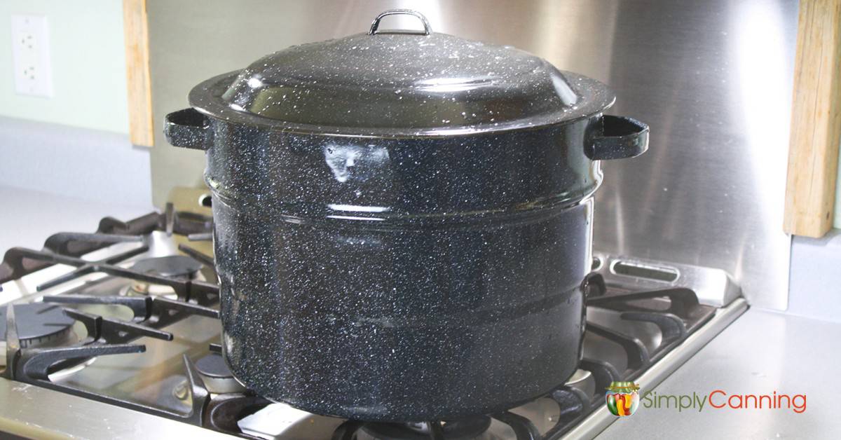 Black graniteware water bath canner sitting on the stove.