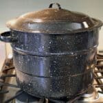 Black speckled graniteware waterbath canner sitting on the stovetop.