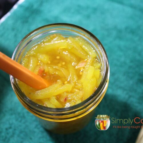 Top view of a jar of sweet zucchini relish with an orange peeler.