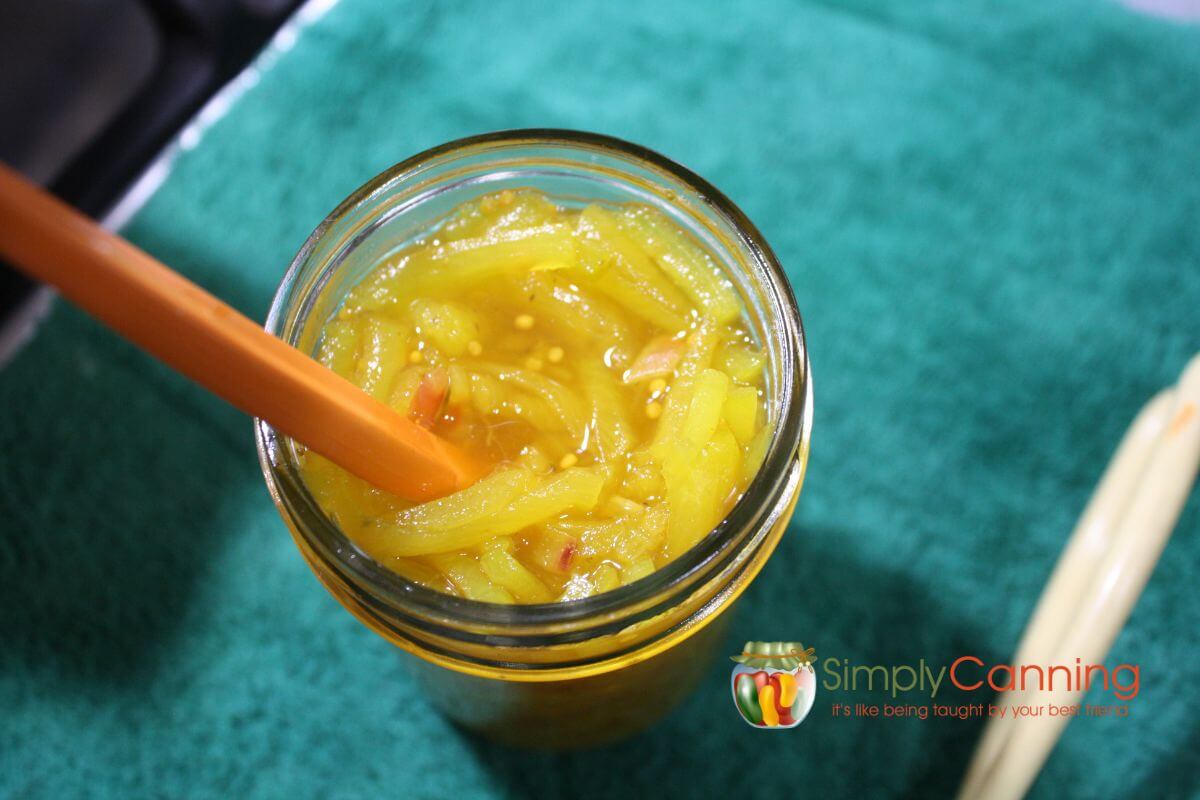 Top view of a jar of sweet zucchini relish with an orange peeler.